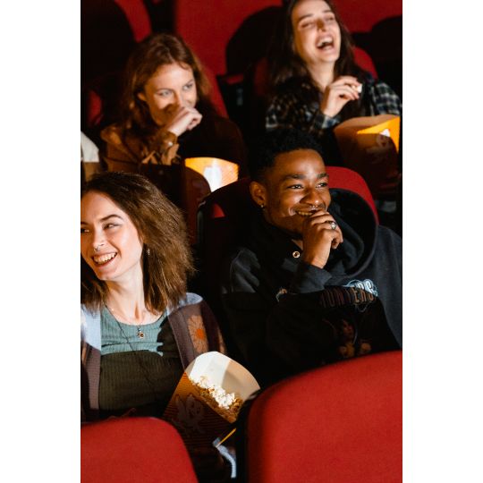 Gens assis au cinéma tenant des seaux de pop-corn